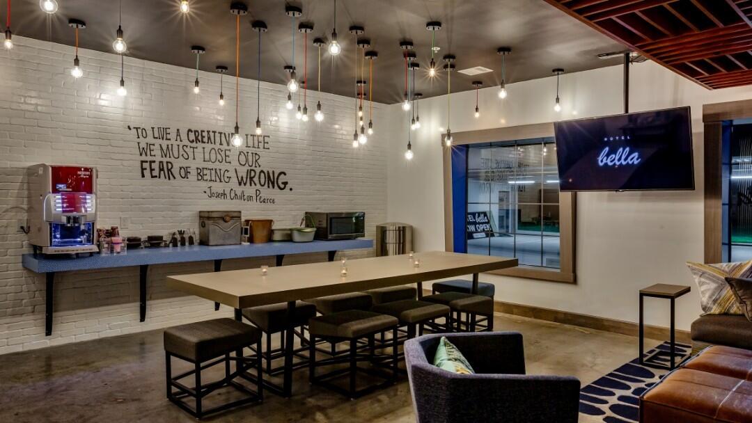 A modern lobby area with a long table, bar stools, and a quote on the wall.