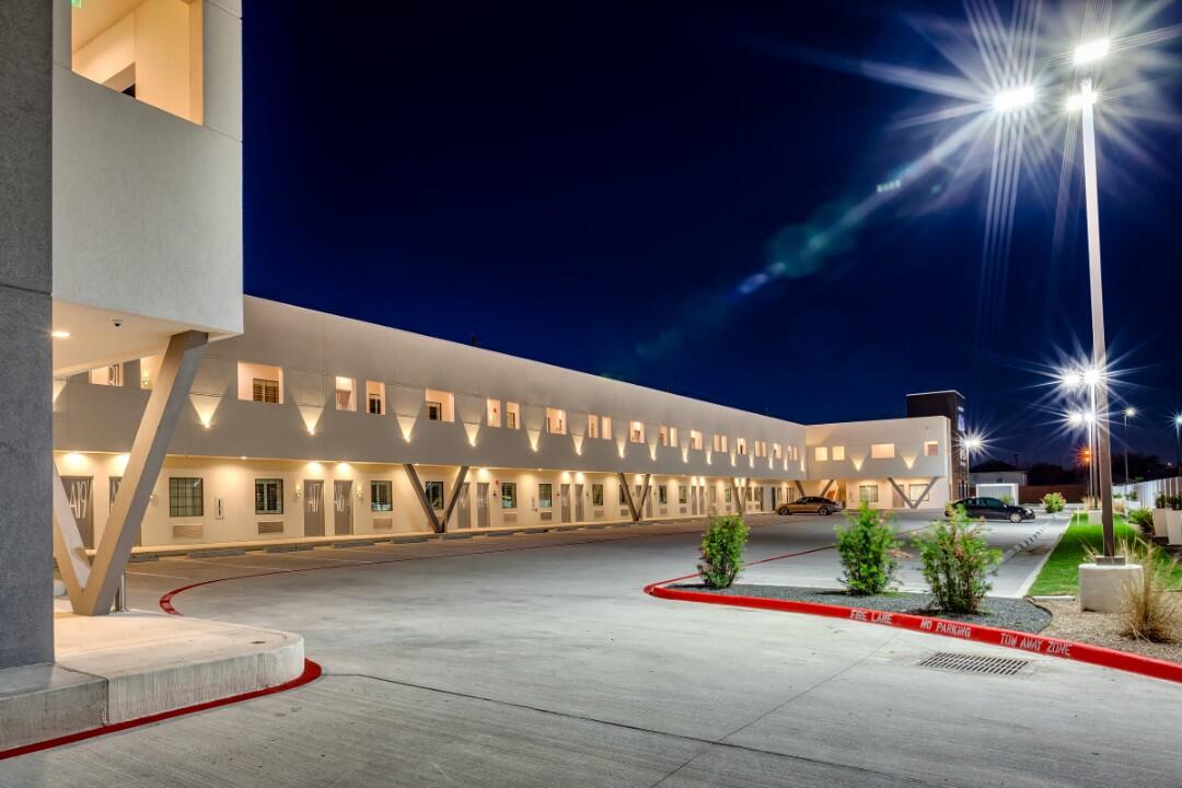 A hotel exterior at night with a parking lot and streetlights.
