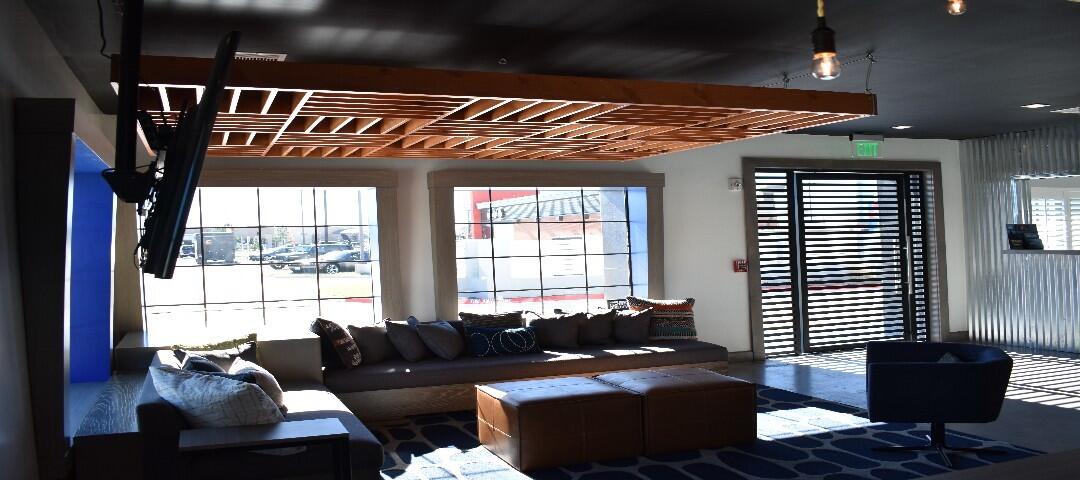 A hotel lobby with a large sofa, coffee table, armchair, and TV