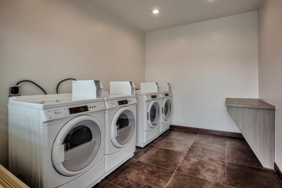 A laundry room with three washing machines and a folding counter.