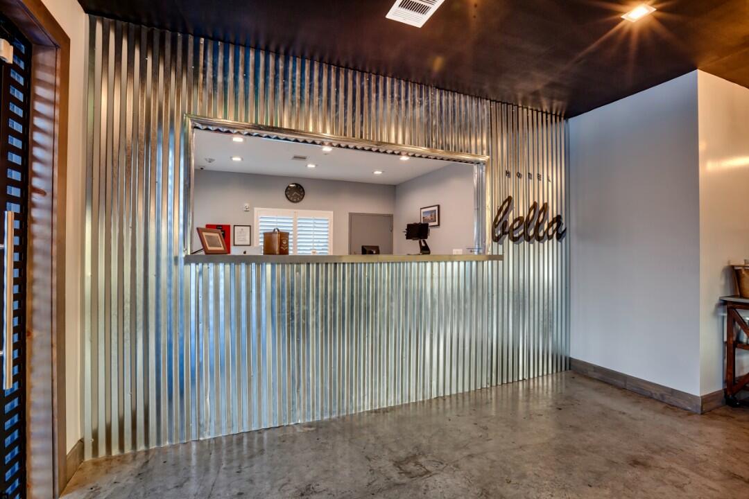 A modern lobby with a metal reception desk and a sign that says 'bella'